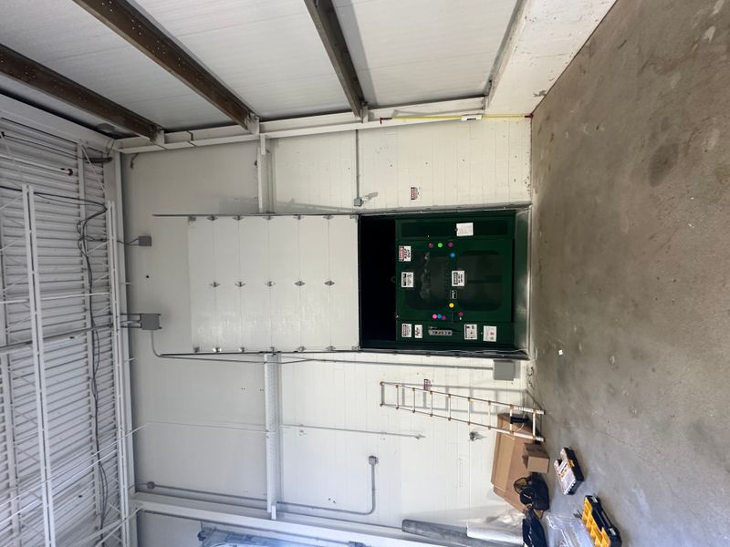 Commercial insulated sectional door half open with opener system visible in warehouse